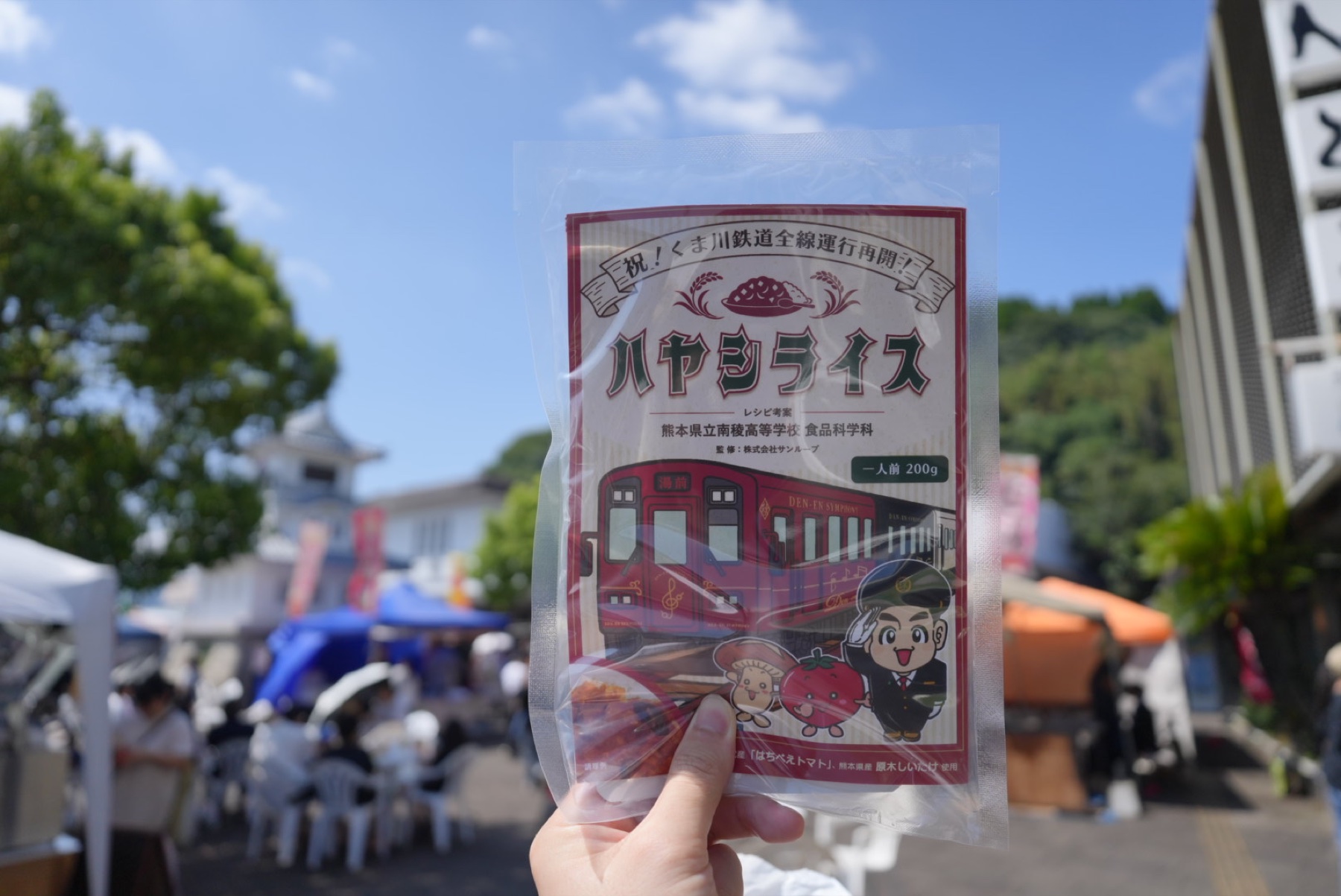 人吉駅前のイベント会場で手に持った、くま鉄応援 ハヤシライスの完成パッケージ